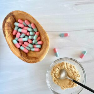 pink and blue capsules in a small wooden bowl